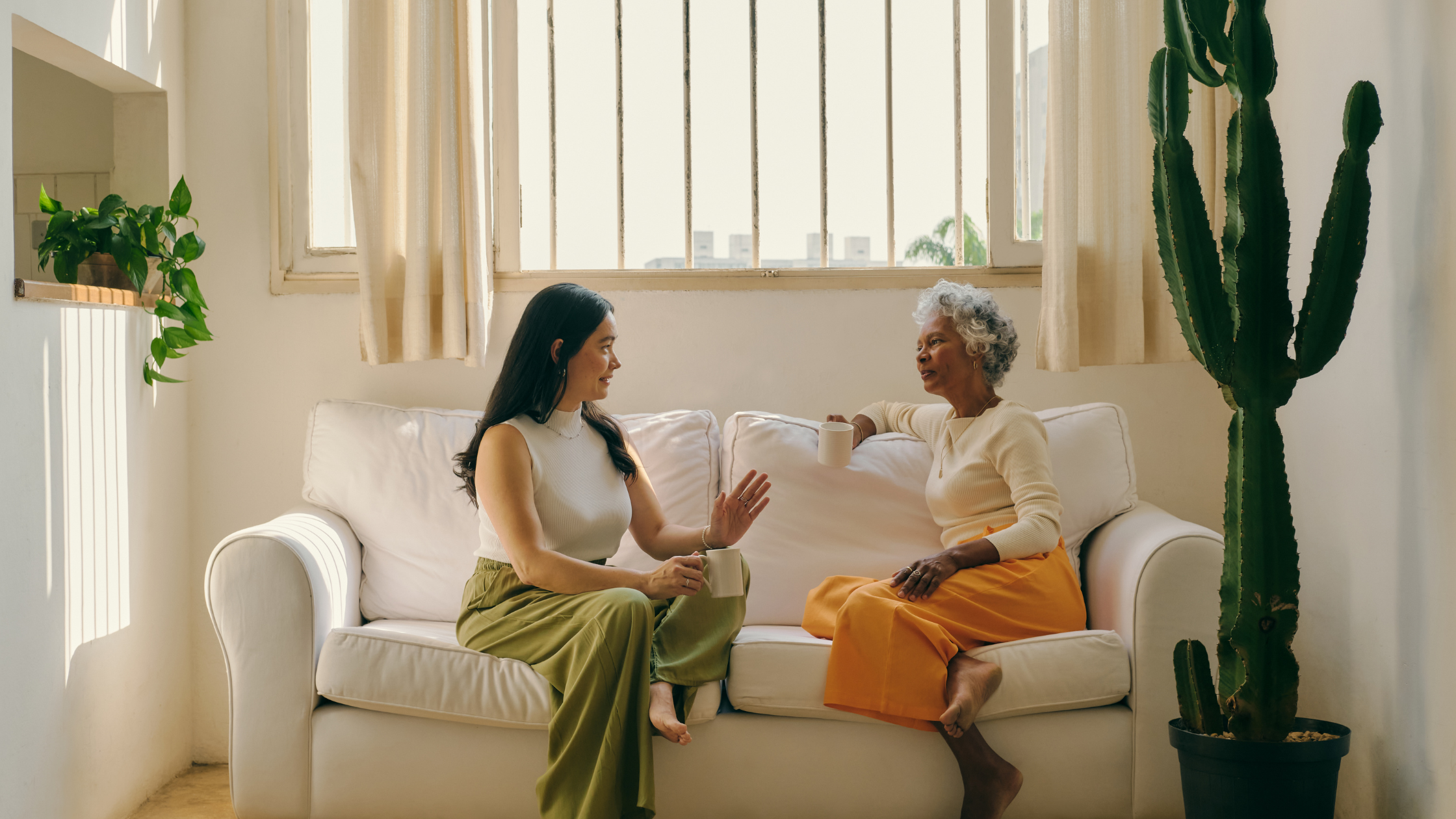 Two women talking to each other while sitting on a couch