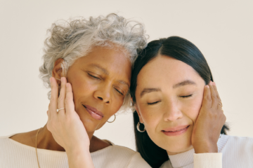 An old and a younger woman cheek-to-cheek and holding the other's face