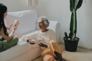 two women talking and holding a book